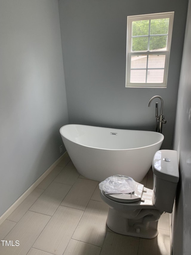 bathroom with toilet and a freestanding tub