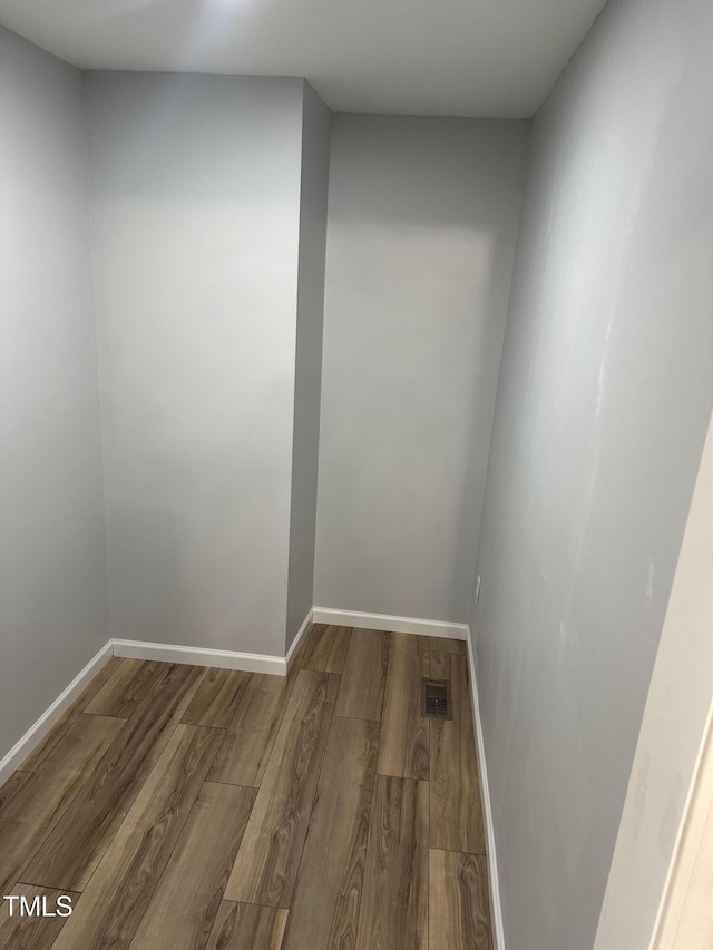 unfurnished room with baseboards, visible vents, and wood finished floors