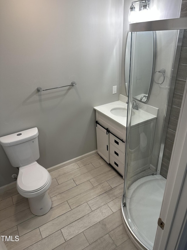 bathroom with wood finish floors, vanity, toilet, baseboards, and a shower stall
