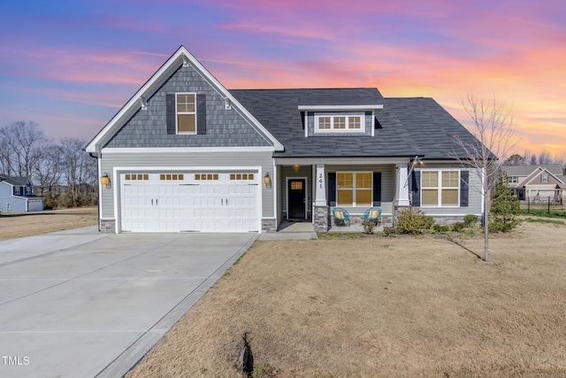 view of front of property featuring stone siding, covered porch, and driveway