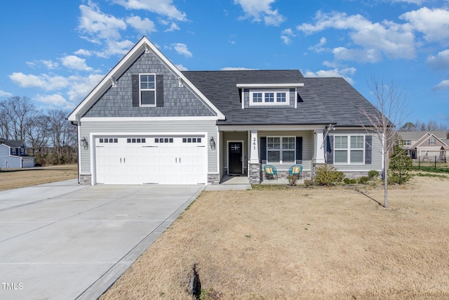 view of front facade with driveway, stone siding, a front yard, a garage, and covered porch