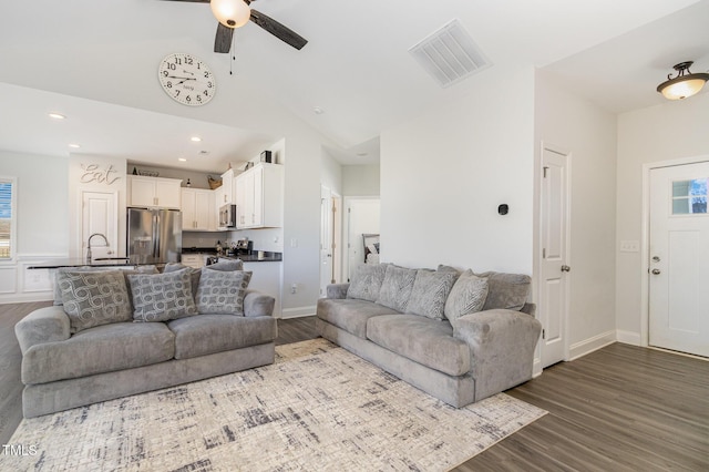 living room with dark wood-type flooring, lofted ceiling, a ceiling fan, and visible vents