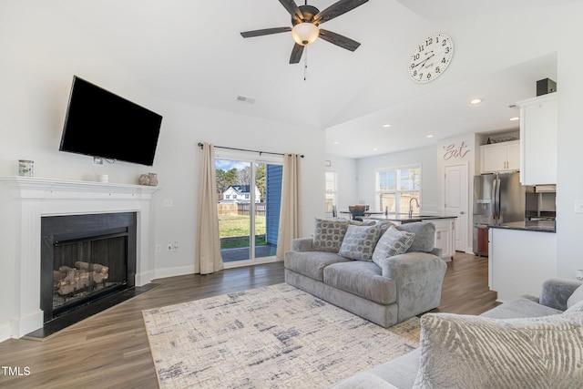 living room featuring a wealth of natural light, dark wood-style floors, and ceiling fan