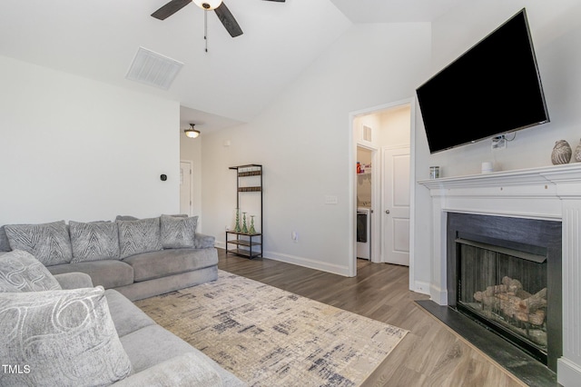 living area with high vaulted ceiling, a ceiling fan, visible vents, wood finished floors, and baseboards