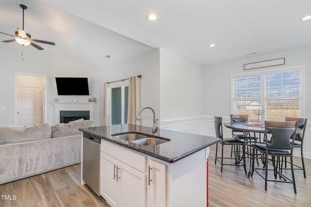 kitchen featuring ceiling fan, a fireplace, dishwasher, a sink, and open floor plan