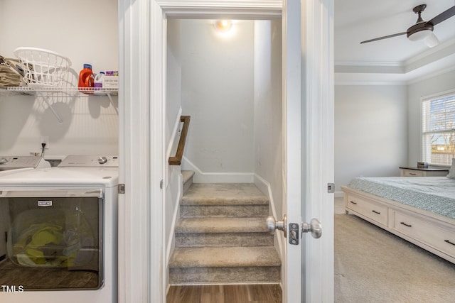 stairs featuring baseboards, a raised ceiling, ceiling fan, crown molding, and washer and clothes dryer