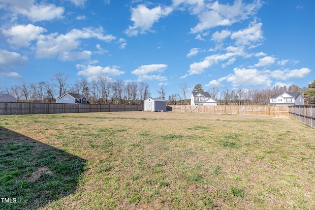view of yard featuring a storage shed, an outbuilding, and a fenced backyard
