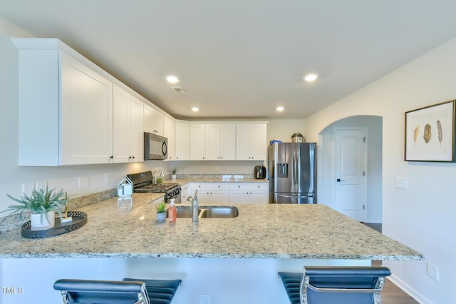 2065 Alderman Way, Creedmoor, NC 27522 - kitchen with a kitchen bar, a peninsula, white cabinetry, and stainless steel appliances