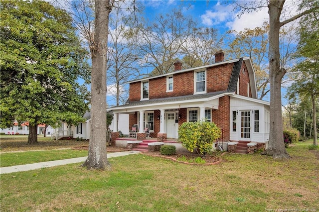 416 N Main St, Raeford, NC 28376 - view of front of home with a chimney, a front yard, brick siding, a gambrel roof, and covered porch