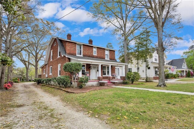 416 N Main St, Raeford, NC 28376 - dutch colonial with a chimney, dirt driveway, a front yard, brick siding, and a porch