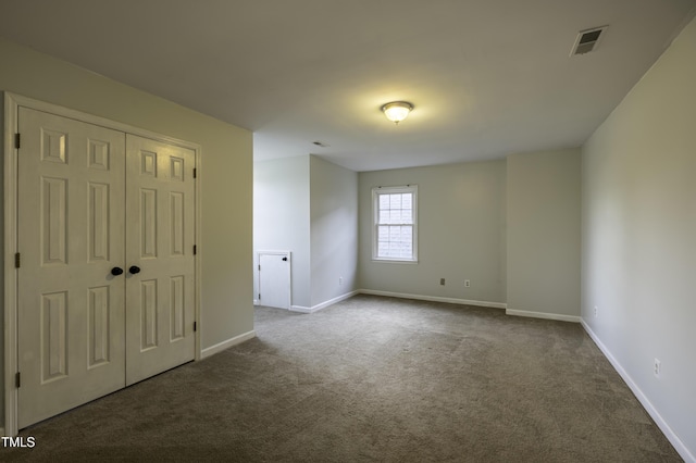unfurnished room featuring dark colored carpet, visible vents, and baseboards