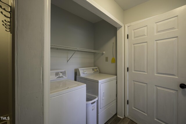 clothes washing area with dark wood finished floors, washer and dryer, and laundry area