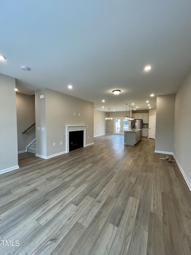 413 Diversity Way, Raleigh, NC 27610 - unfurnished living room featuring wood finished floors, recessed lighting, baseboards, a fireplace, and stairway