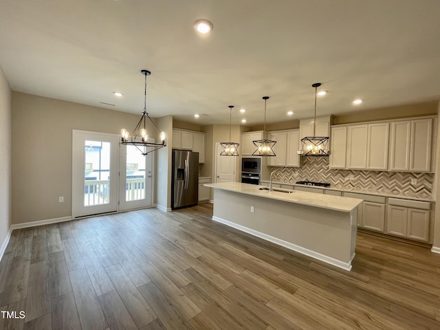 413 Diversity Way, Raleigh, NC 27610 - kitchen with appliances with stainless steel finishes, tasteful backsplash, a chandelier, a center island with sink, and dark wood-style flooring