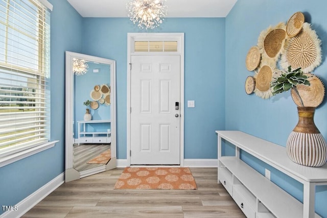 foyer featuring baseboards, an inviting chandelier, and light wood-style floors
