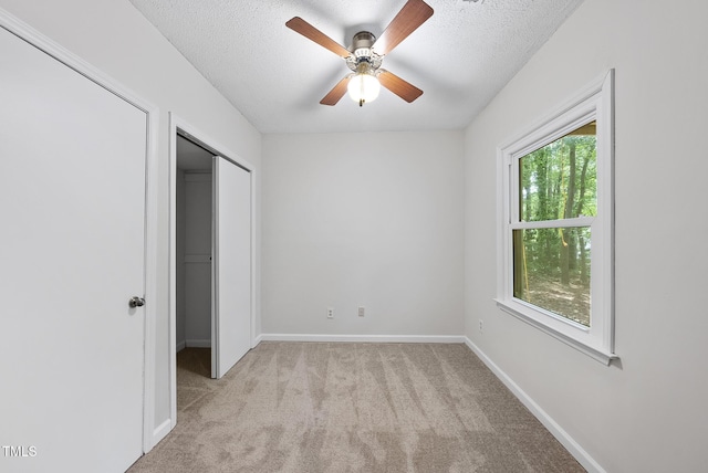unfurnished bedroom featuring ceiling fan, a textured ceiling, baseboards, and light carpet