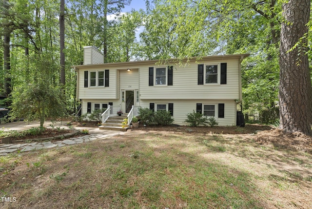 split foyer home with a chimney and a front yard