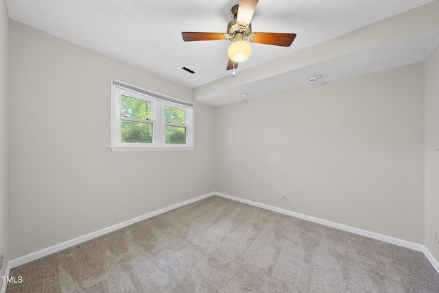 carpeted spare room featuring baseboards and a ceiling fan