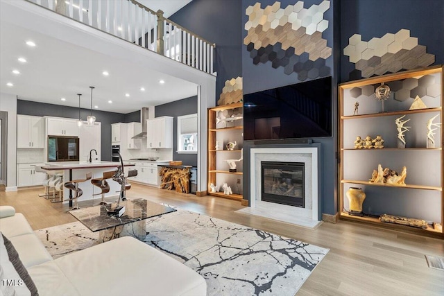 956 The Parks Dr, Pittsboro, NC 27312 - living room featuring recessed lighting, a high end fireplace, light wood-style floors, and a high ceiling
