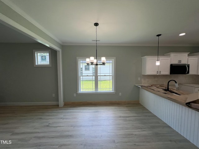 502 S Vance St, Fremont, NC 27830 - kitchen featuring stainless steel microwave, white cabinets, hanging light fixtures, a chandelier, and light wood-style floors