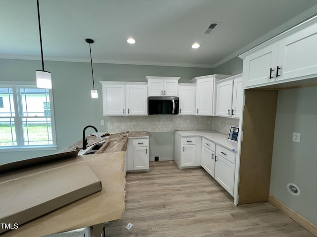 502 S Vance St, Fremont, NC 27830 - kitchen with stainless steel microwave, ornamental molding, backsplash, pendant lighting, and white cabinets