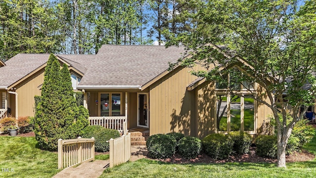 chalet / cabin with a front lawn, covered porch, and roof with shingles