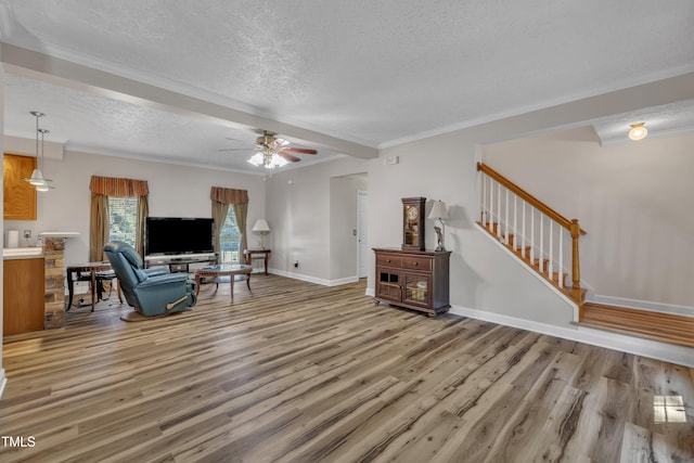2265 Bud Lipscomb Rd, Willow Springs, NC 27592 - living room featuring a textured ceiling, light wood finished floors, ceiling fan, stairs, and ornamental molding