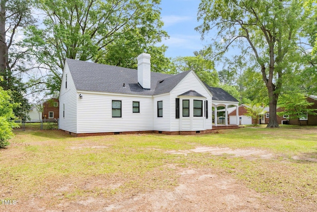 rear view of property featuring crawl space, a chimney, roof with shingles, fence, and a yard