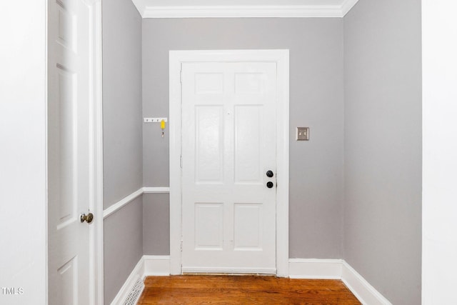 doorway to outside featuring crown molding, baseboards, and wood finished floors