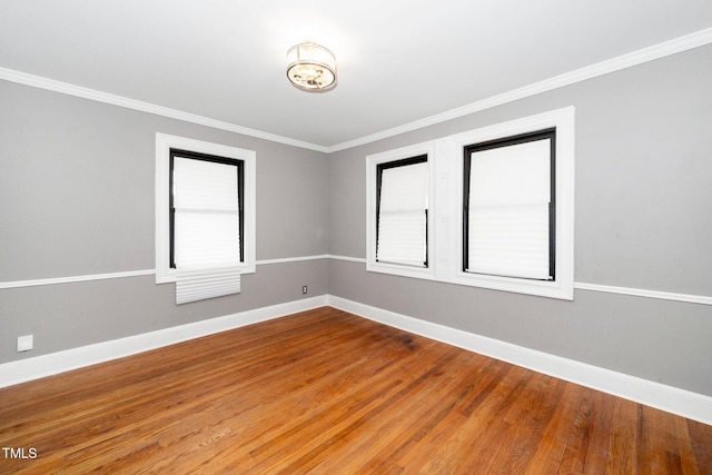 spare room with crown molding, baseboards, plenty of natural light, and wood finished floors