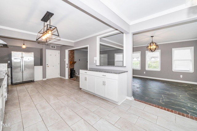 kitchen featuring crown molding, freestanding refrigerator, an inviting chandelier, baseboards, and dark stone counters