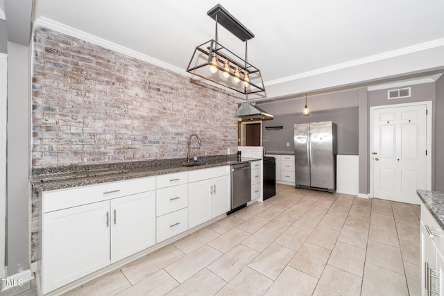 kitchen featuring crown molding, appliances with stainless steel finishes, a sink, dark stone counters, and visible vents