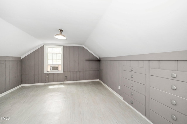 bonus room featuring baseboards, wood walls, wood finished floors, and vaulted ceiling