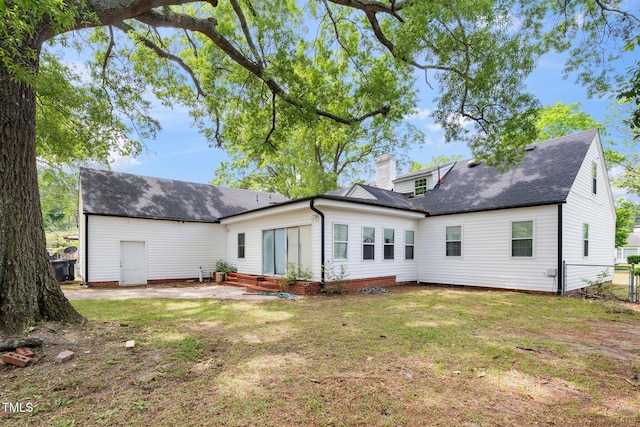 rear view of property featuring a chimney, a patio area, fence, a yard, and a shingled roof