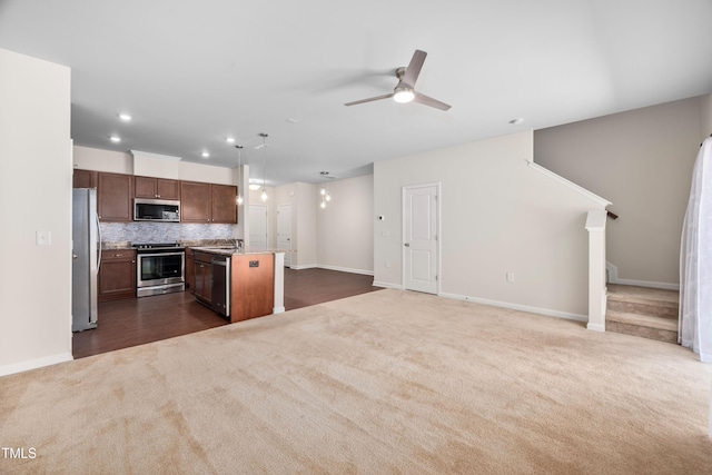 kitchen with a kitchen island, appliances with stainless steel finishes, open floor plan, decorative backsplash, and dark colored carpet