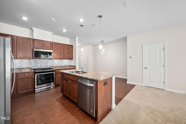 kitchen featuring visible vents, a sink, appliances with stainless steel finishes, a center island with sink, and decorative backsplash
