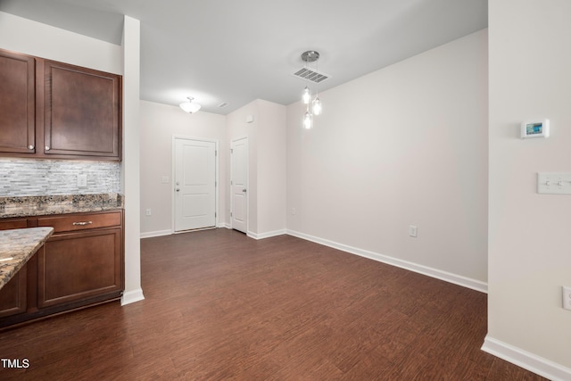 unfurnished dining area with dark wood-type flooring, visible vents, and baseboards