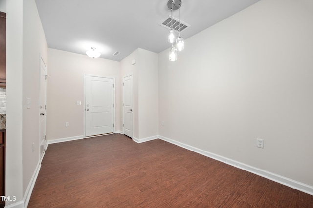 empty room with visible vents, baseboards, and dark wood-style floors