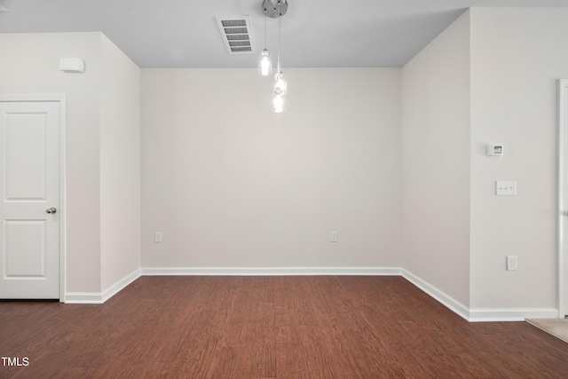 spare room featuring visible vents, baseboards, and wood finished floors