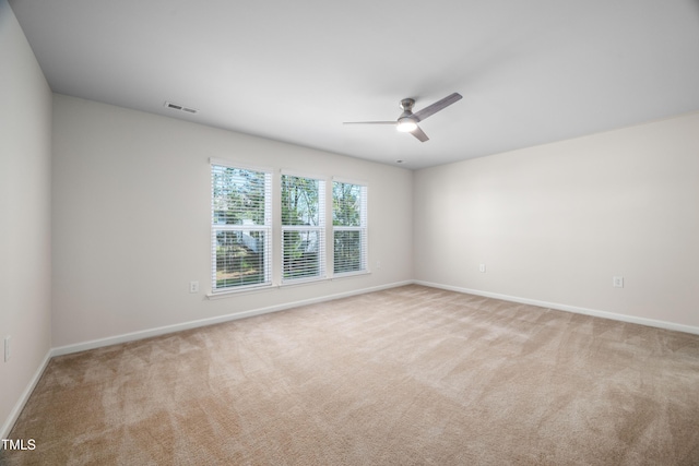 carpeted spare room featuring visible vents, baseboards, and a ceiling fan