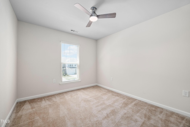 carpeted spare room with visible vents, baseboards, and a ceiling fan