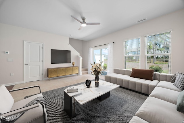 carpeted living area with visible vents, baseboards, and a ceiling fan
