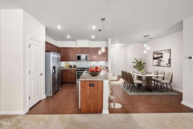 kitchen featuring tasteful backsplash, baseboards, a breakfast bar area, dark carpet, and stainless steel appliances