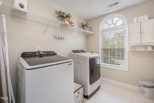 clothes washing area with visible vents, washer and clothes dryer, laundry area, and baseboards