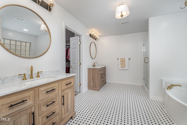 bathroom featuring a shower stall, two vanities, a sink, and visible vents