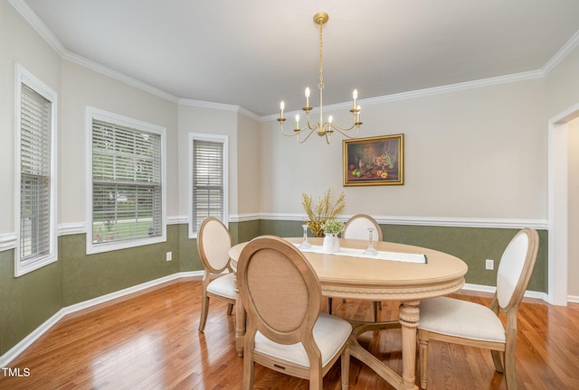 dining space with ornamental molding, baseboards, a chandelier, and wood finished floors