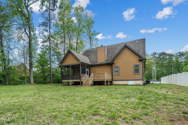 back of house featuring a sunroom, a lawn, a chimney, fence, and roof with shingles