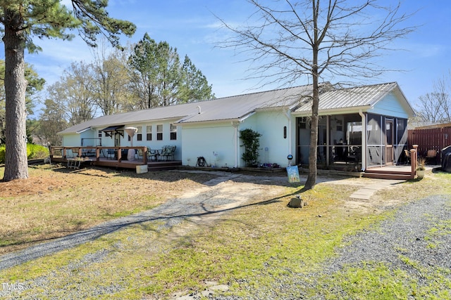 back of property featuring a sunroom, metal roof, fence, stucco siding, and a wooden deck