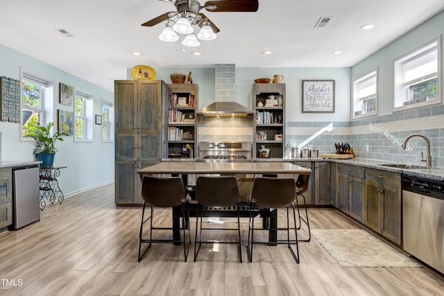 kitchen featuring refrigerator, wall chimney range hood, open shelves, dishwasher, and a sink