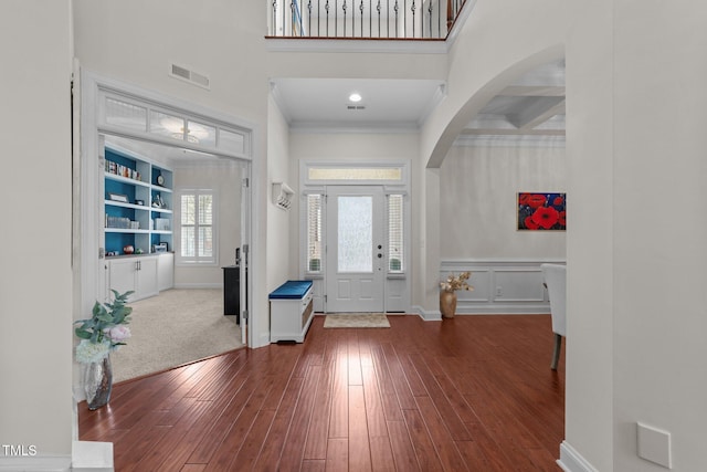 5928 Terrington Ln, Raleigh, NC 27606 - entrance foyer with crown molding, a decorative wall, arched walkways, visible vents, and wood finished floors